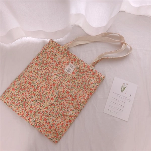 Close-up of floral cotton tote bag with white woven label on soft wrinkled fabric