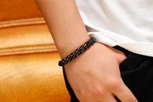 Gros plan d'un bracelet en acier titane noir à maille dragon au poignet d'un homme décontracté
