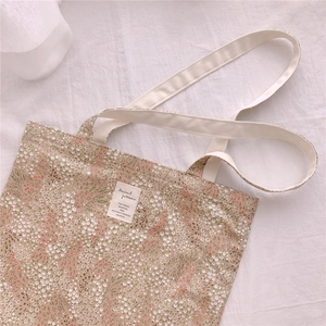 Macro view of floral cotton tote bag texture and white woven label on cream fabric