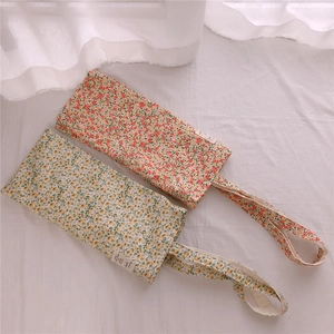 Close-up of floral cotton storage pouches with drawstring handles and woven labels