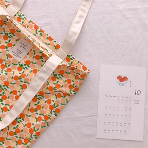 Close-up of cream cotton tote bag with orange fruit print and woven handle