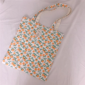 Detail of floral canvas tote bag featuring orange patterns and a minimalist woven label