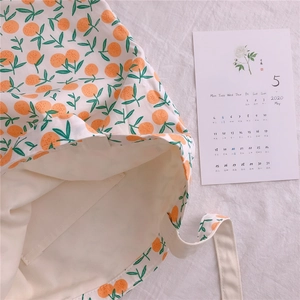 Detailed close-up of cream canvas tote bag with fresh orange and green leaf pattern
