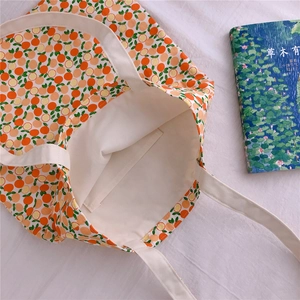 Detail of vibrant orange fruit print canvas tote bag with functional inner pocket