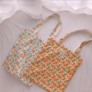 Close-up of floral cotton tote bags with orange prints and woven handles