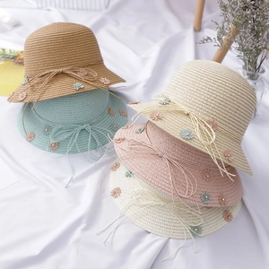 Detail of woven straw cloche hats with 3D daisy flowers and bows in multiple colors