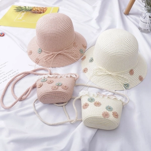Close-up of kids straw sun hat and matching bag with daisy appliques and lace details