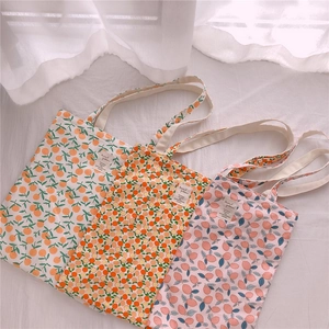 Detailed view of floral cotton tote bags with orange and berry patterns on white fabric