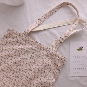 Detail of floral canvas tote bag featuring pink cherry pattern and rectangular woven label