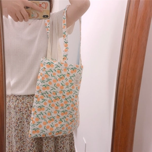 Detail of canvas tote bag showing the fresh orange print and side label in close-up shot