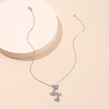 Detail of silver chain necklace with three sparkling butterfly charms on a pedestal