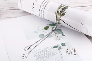 Close-up of silver layered necklace with heart bead and couple figure pendants