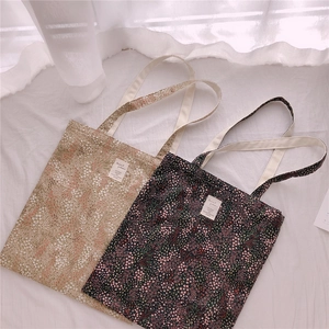 Close-up of floral canvas tote bags in beige and navy showing detailed fabric texture