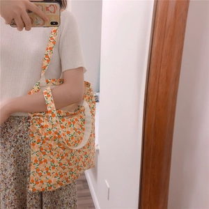 Floral canvas tote bag with orange fruit print shown being worn as a shoulder bag