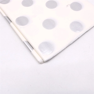 Makroaufnahme von weißem Geschenkpapier mit glänzenden silbernen Metalleffekt-Punkten