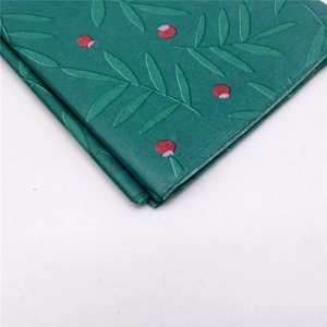 Detailansicht von grünem Geschenkpapier mit botanischem Blatt- und Beerenmuster