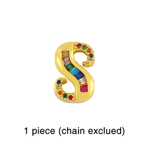 Macro detail of golden letter S pendant featuring colorful rainbow gemstone inlay