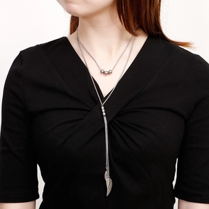 Double-layered silver titanium necklace with beaded chain and feather pendants on model