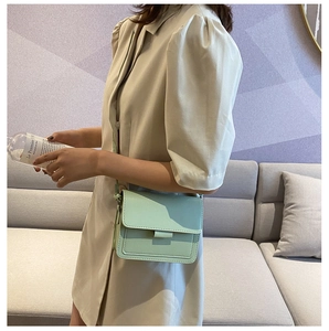 Detail of mint green leather crossbody bag shown on model with clean stitching and flap