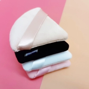Set of four colorful velvet powder puffs in beige, black, blue, and pink for makeup