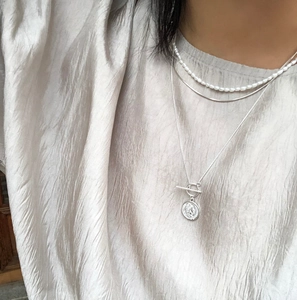 Detailed layered look featuring a pearl choker, silver snake chain and coin pendant necklace