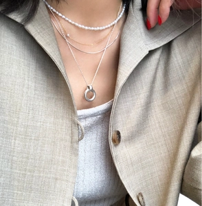Detail of layered jewelry featuring small freshwater pearls and gold metal chain on a model