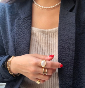 Close-up of layered 925 silver pearl necklace and gold rings set on female model