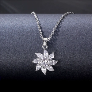 Elegant silver flower necklace with marquise-cut zircons hanging on a textured display