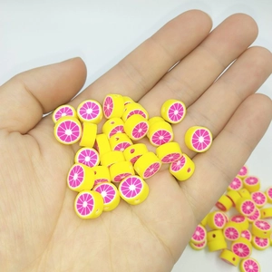 Detailed macro view of 10mm yellow lemon polymer clay beads with pink centers for DIY