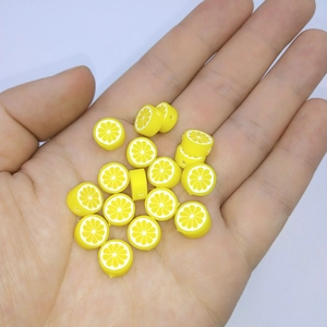 Macro shot of 10mm yellow lemon polymer clay beads held in palm for DIY jewelry making