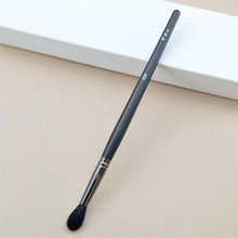 Detail of tapered makeup brush 228 with matte grey handle on minimalist background