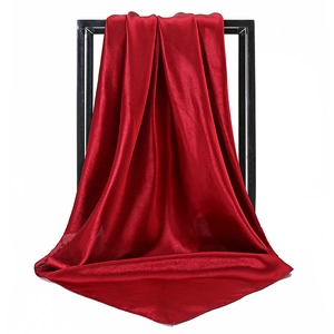 Detailed view of dark red satin square scarf hanging elegantly on a black frame
