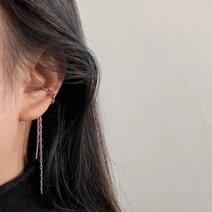 Detail view of silver ear cuff with long metallic fringe chain and dangling bar design