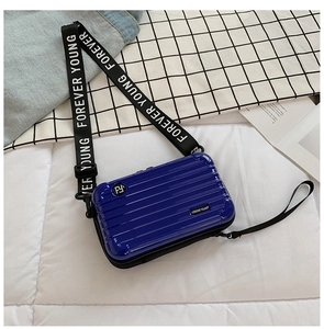 Detail of a mini suitcase cross-body bag in navy blue with Forever Young strap