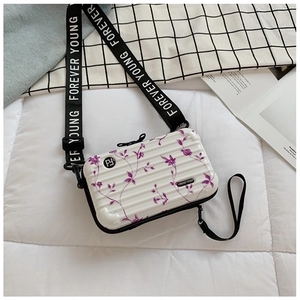 Close-up of white hardshell mini suitcase bag with purple floral print and wide strap