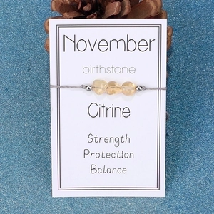 Detail view of November birthstone bracelet featuring raw Citrine stones on grey woven cord