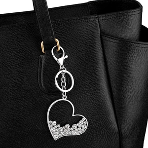 Silver heart-shaped rhinestone keychain pendant on black leather bag with metal hardware
