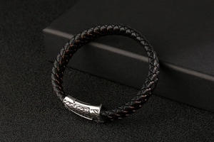 Macro shot of black braided leather bracelet with embossed vintage silver metal clasp