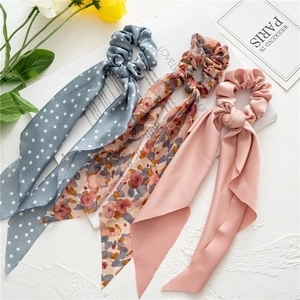 Close-up of three elegant floral and polka dot chiffon hair scrunchies with long ribbons