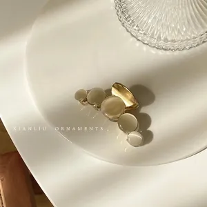 Detail showing five white cat-eye stones on a gold alloy hair claw clip on porcelain