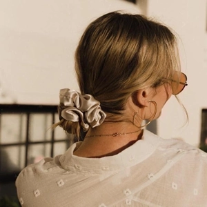 Detailed view of a champagne satin scrunchie styled on a low bun in natural light