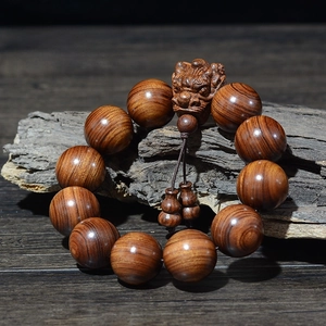 Détail macro de perles en bois de santal avec breloque dragon et texture peau de tigre
