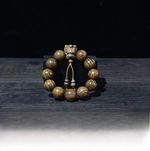 Détail macro du bracelet en perles de bois avec pendentif lion sculpté et grain de bois fin