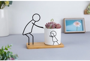 Detail of Nordic ceramic succulent planter with abstract metal figure on bamboo tray
