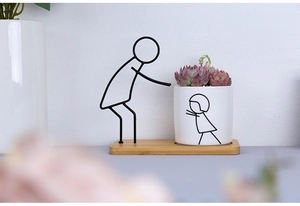 Detail of Nordic ceramic planter with black iron figure stand and bamboo base