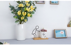 Close-up of minimalist ceramic planter with black line art and iron figure stand