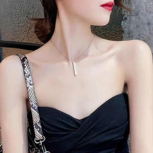 Detail showing a minimalist vertical shell bar pendant necklace on a model's neck
