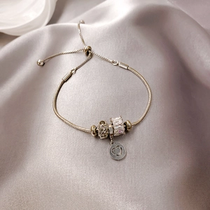 Silbernes Schlangenarmband mit funkelnden Kristallperlen und Herzanhänger auf Seidenstoff