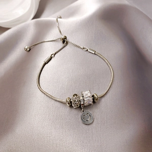 Dettaglio del bracciale fiore in opale argento con ciondolo a cuore su seta grigia