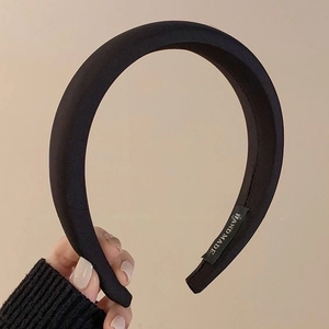 Detail shot of black padded satin headband featuring the white Hand Made inner label tag